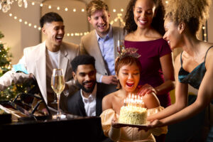 Group Of Friends Around Piano Celebrating Woman's Birthday With Cake